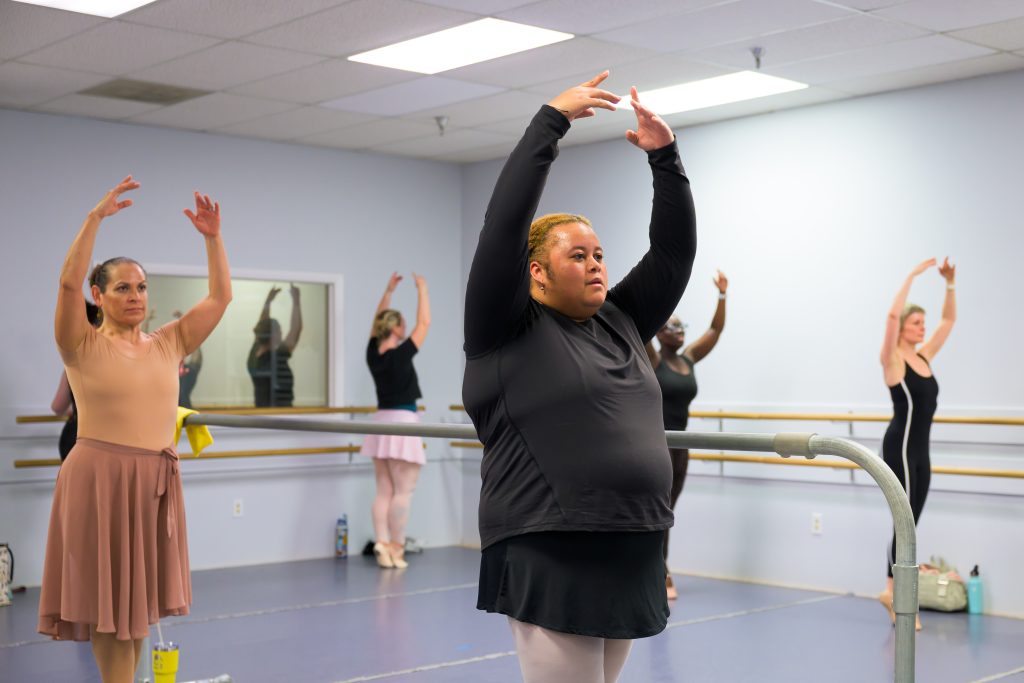 Adult Ballet 2 students at the barre warming up for class.  Here you can see them working on their sousou balance at the ballet barre in Mrs. Heidi's class.