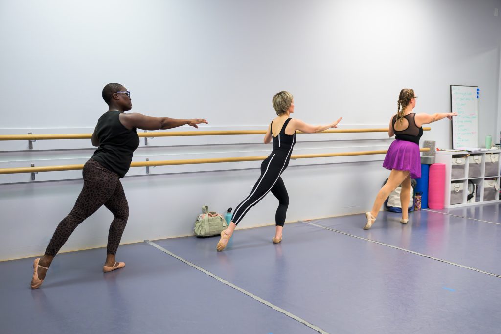 Adult Ballet 1 students at the barre for warmup working on a tendu combination.