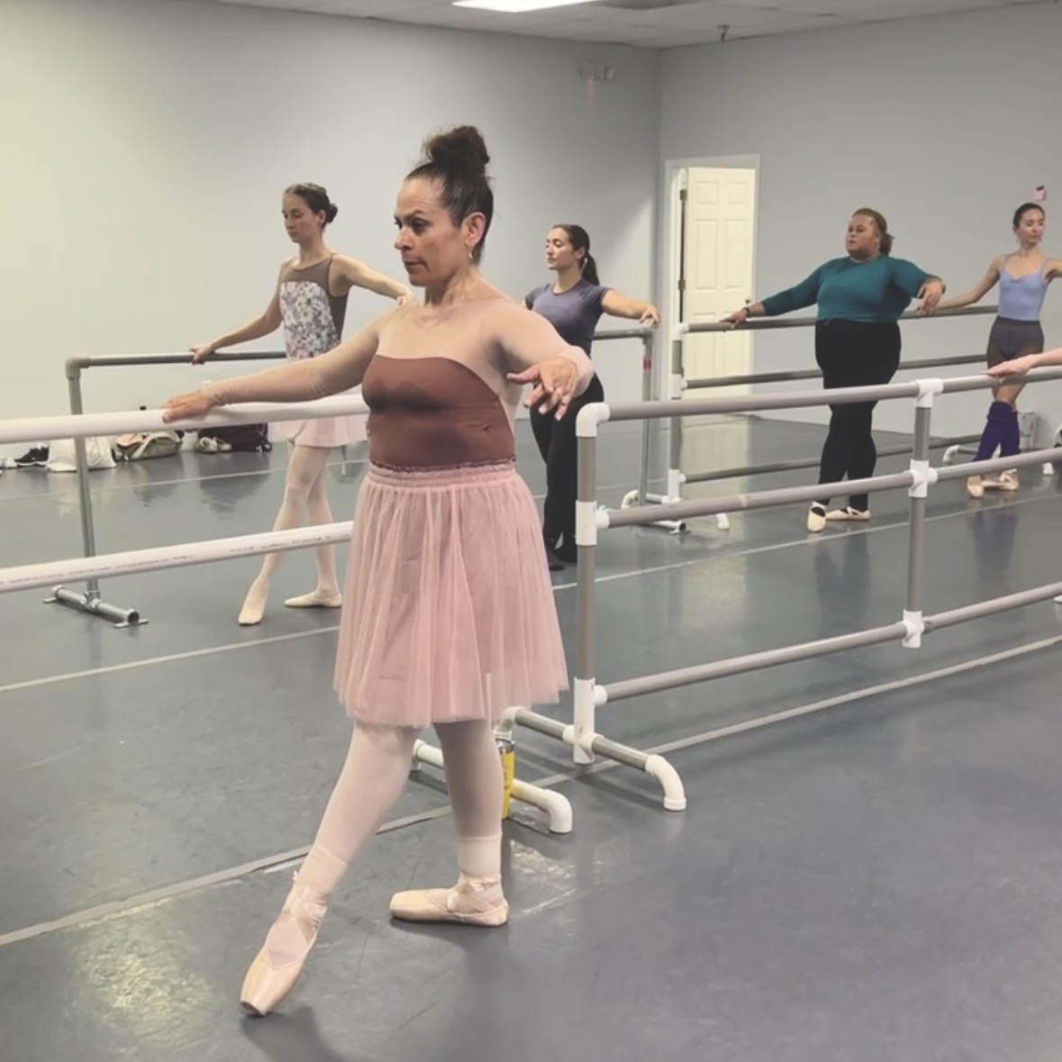 Adult beginner pointe students at the barre warming up their body and feet in pointe shoes.
