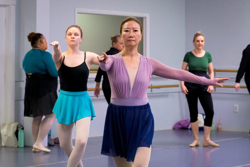 Adult ballet students attending a ballet class.  Here they are moving across the floor.